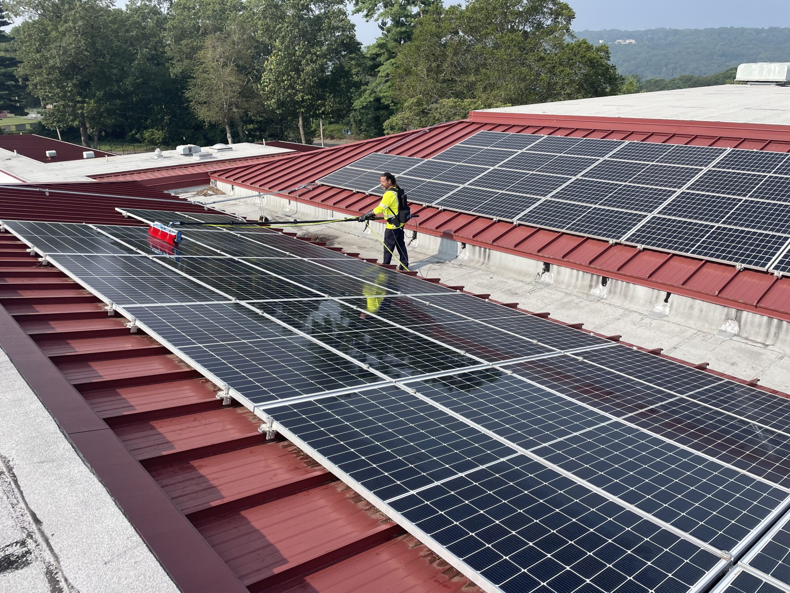 Professional technician cleaning a rooftop solar panel system