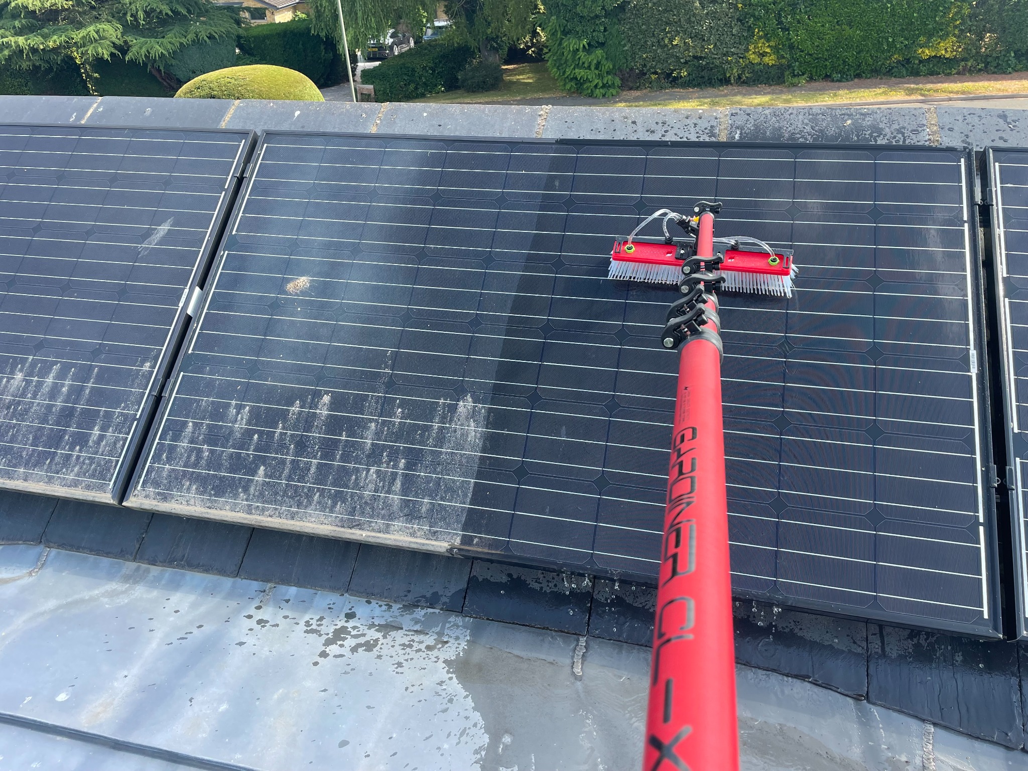 Professional residential solar panel cleaning showing soiling being removed with specialist brush equipment