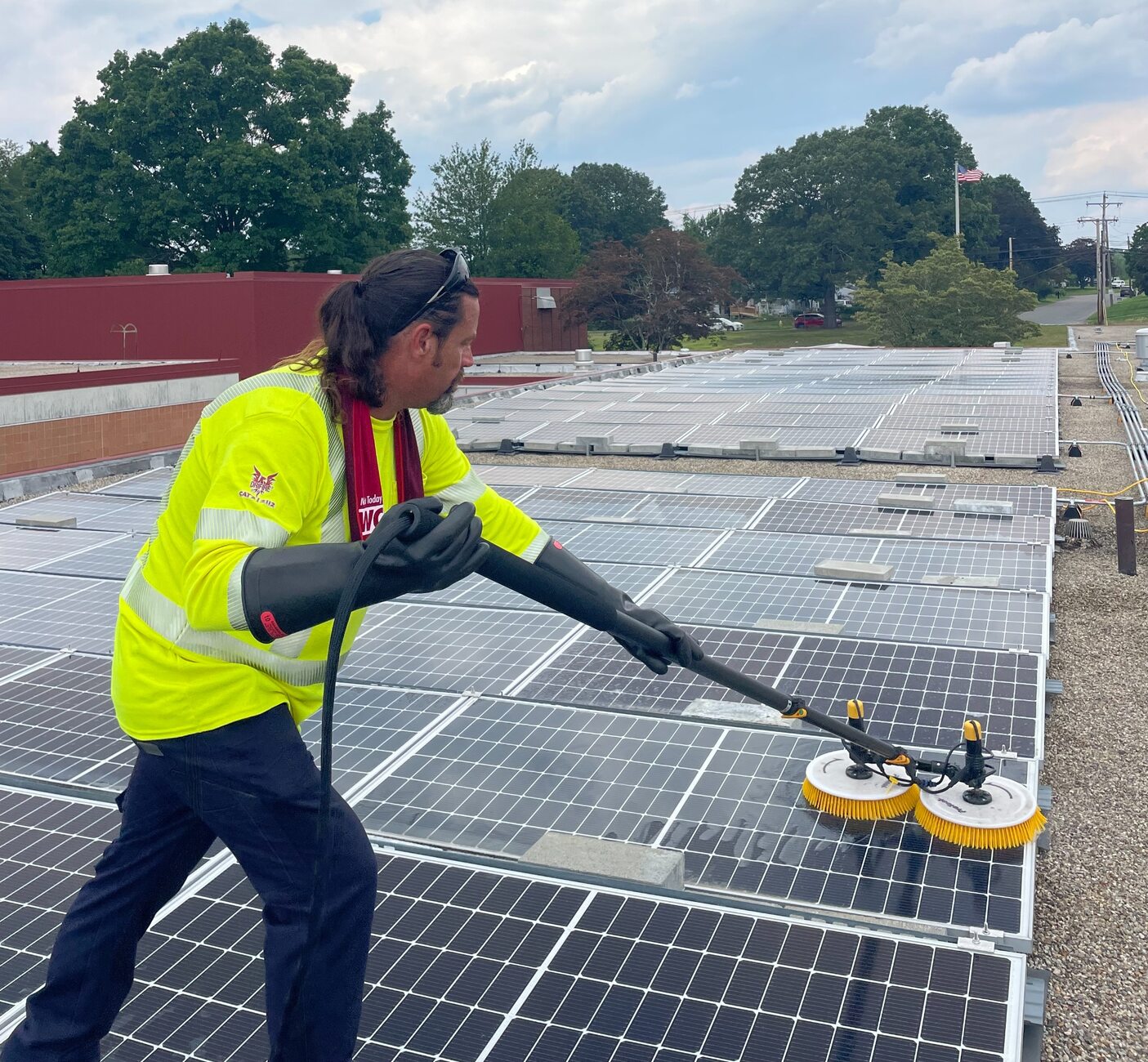 CSSA solar panel cleaning technician wearing high-visibility PPE and protective gloves during a commercial rooftop clean
